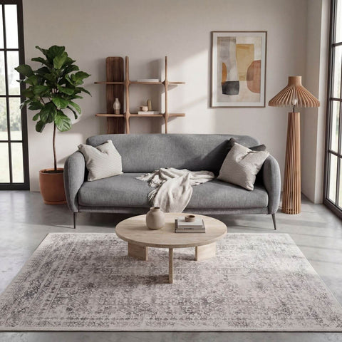 Gray fabric sofa with striped throw pillows and a blanket paired with a cream rug from the montana cream collection