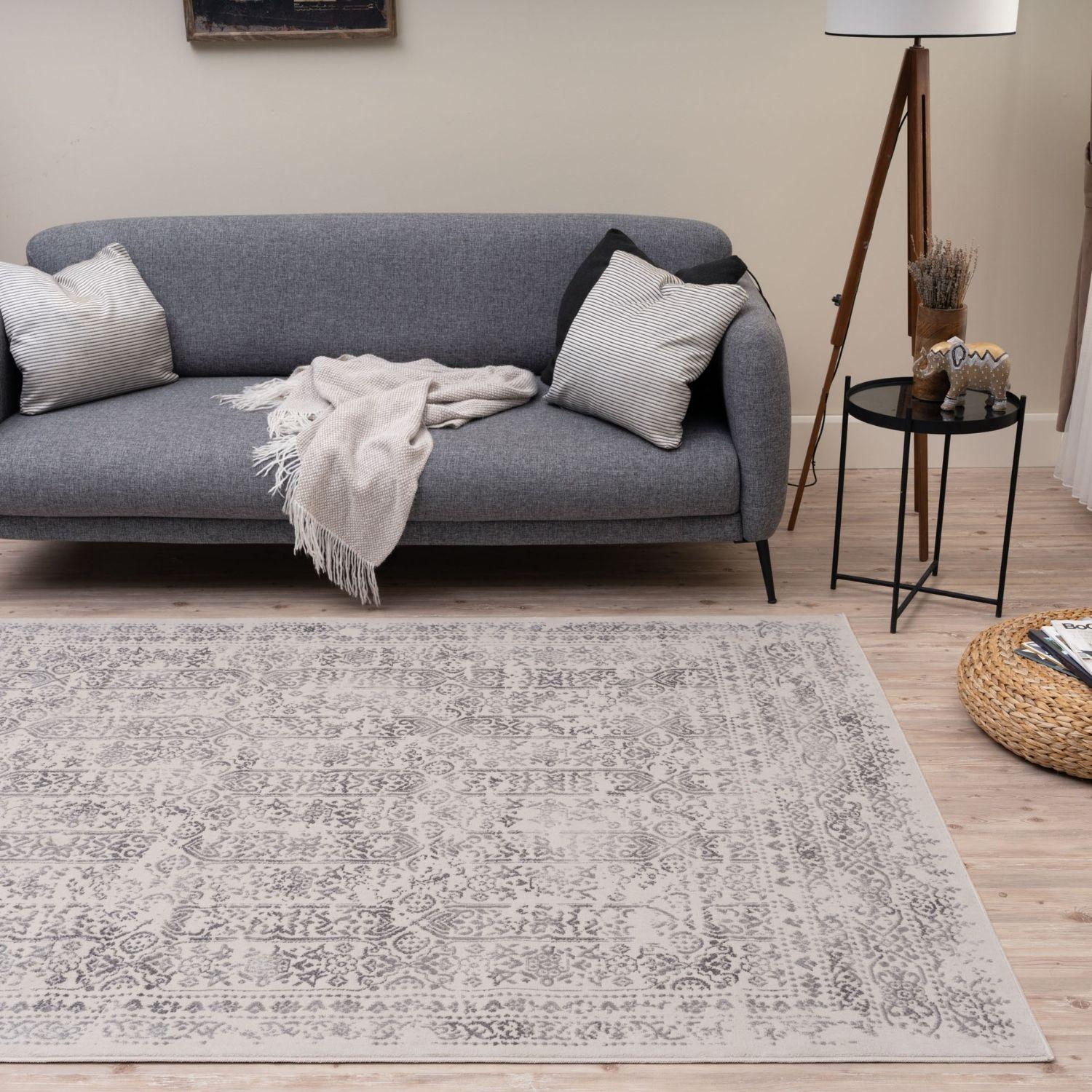 A rectangular vintage-style montana cream rug with a faded gray and white intricate pattern