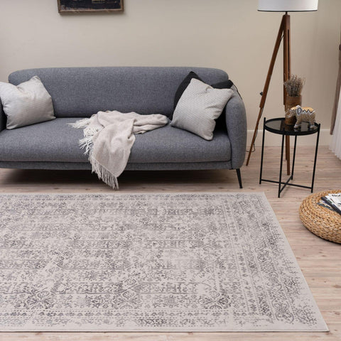 A rectangular vintage-style montana cream rug with a faded gray and white intricate pattern