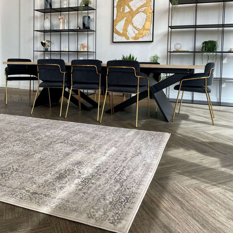 A rectangular vintage-style montana cream rug with faded gray and cream pattern on wooden floor