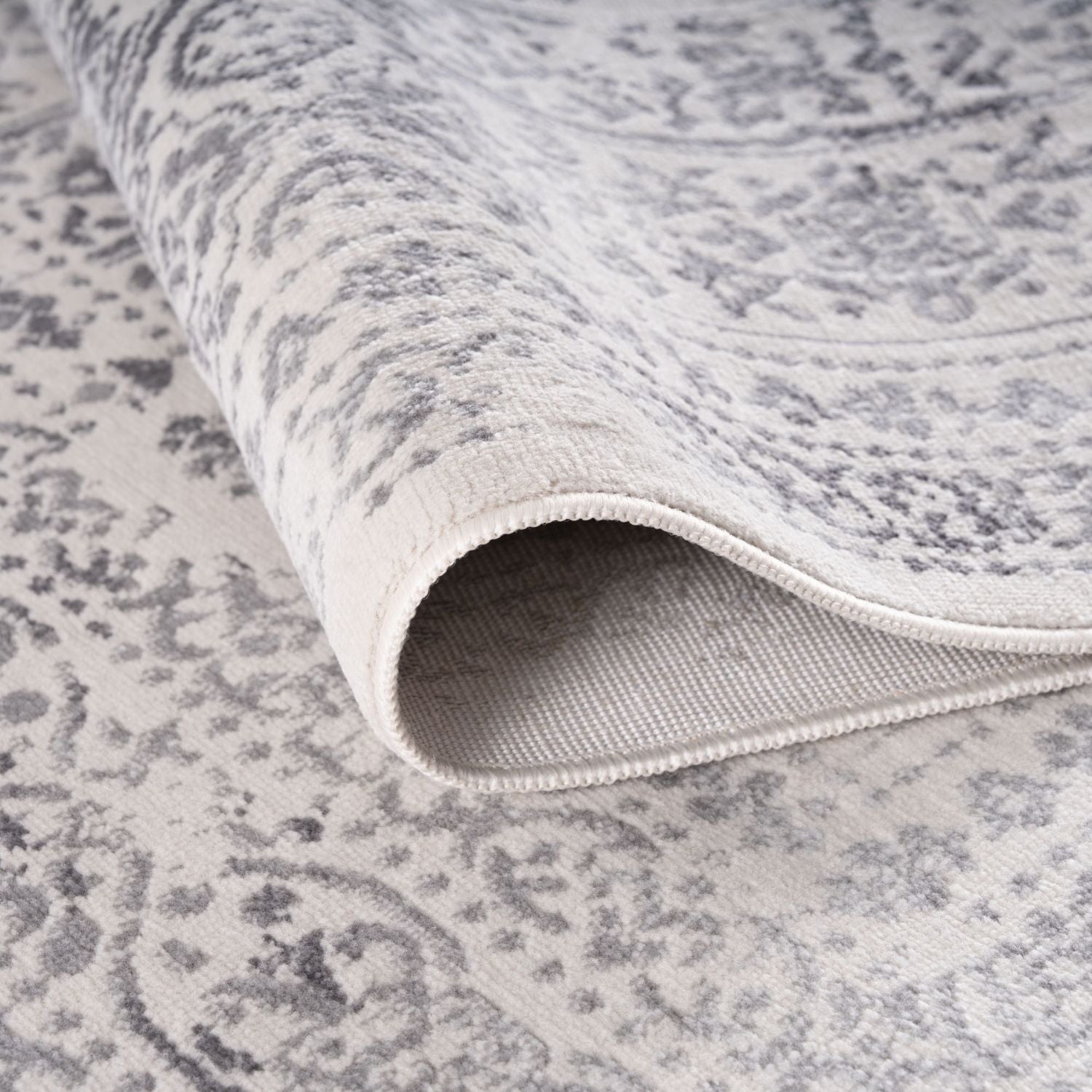 A montana cream rug with a soft off-white base and subtle gray vintage-inspired pattern with stitched edge