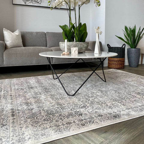 A vintage-style montana cream rug with a faded gray and white intricate pattern on the floor