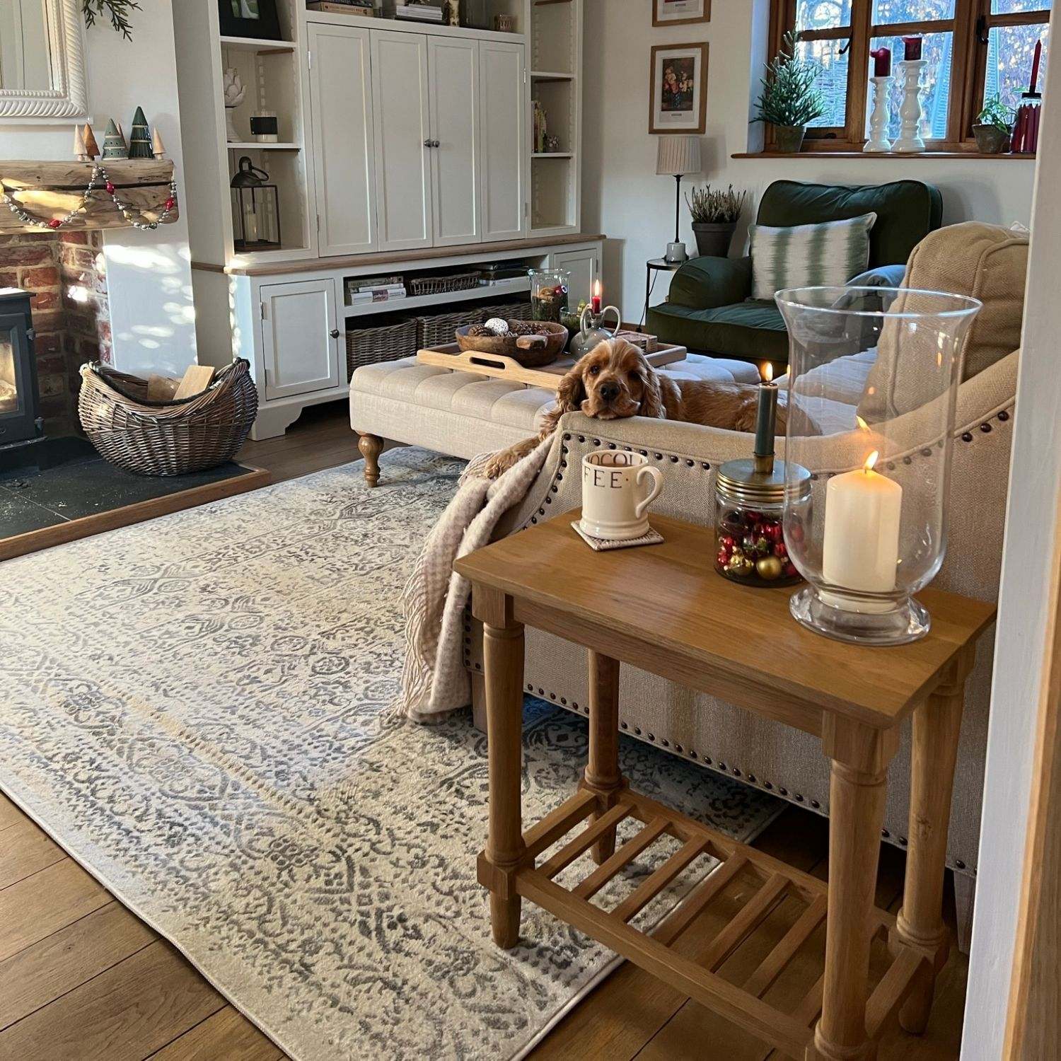 Wooden side table with glass candle holder and white mug on montana cream rug in cream color for cozy decor
