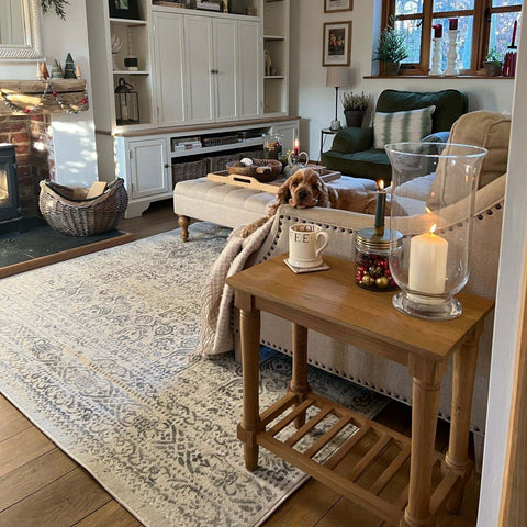Wooden side table with glass candle holder and white mug on montana cream rug in cream color for cozy decor