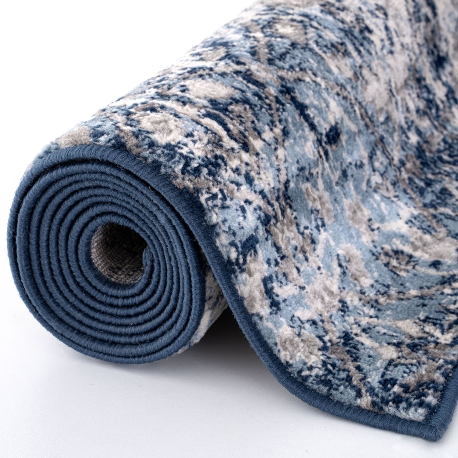 A rolled-up montana vintage navy rug with a distressed blue and beige plush pile and solid navy border