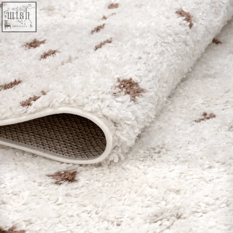 White plush moodi shaggy cream rug with brown tufted accents and woven backing for cozy living spaces