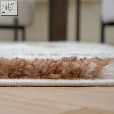 A plush moodi shaggy cream rug with a fluffy texture and a neat cream terra sunhaze stitched border