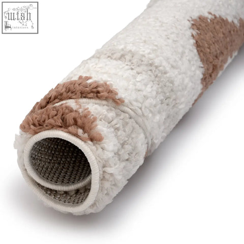 A plush rolled-up moodi shaggy cream rug in cream terra sunhaze color with soft fluffy textured material