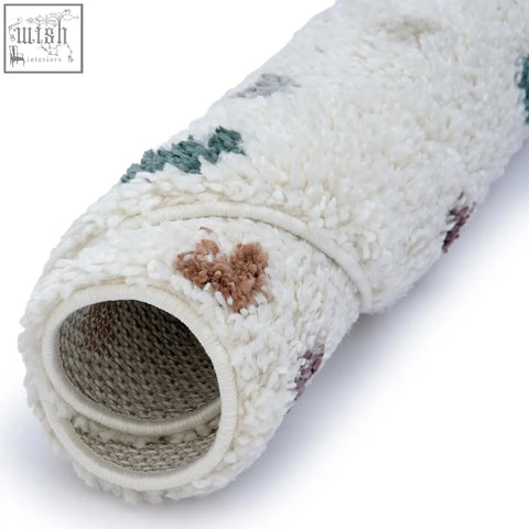 A plush cream-colored moodi shaggy multicolour jubile rug with soft texture and subtle green and brown geometric patterns