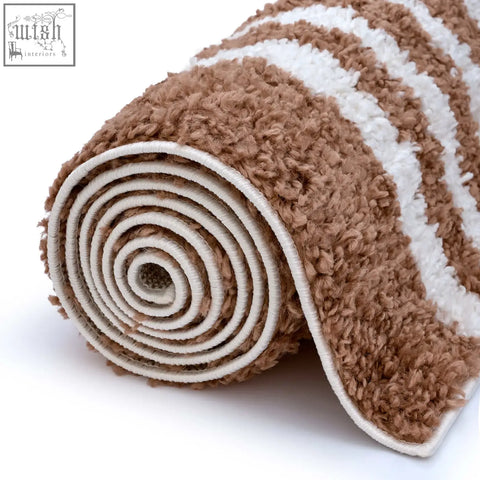 A plush rolled moodi shaggy terra bath mat with soft textured fabric in brown and white stripes terra tawny rug