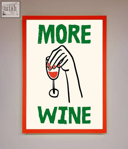 A wine framed print with a bold red border and green more wine text featuring a hand holding a red wine glass