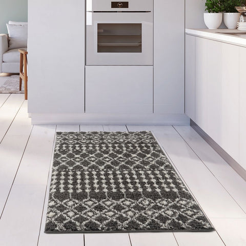 A plush moroccan dark grey shaggy rug with a geometric pattern lies on the floor in front of modern kitchen cabinets