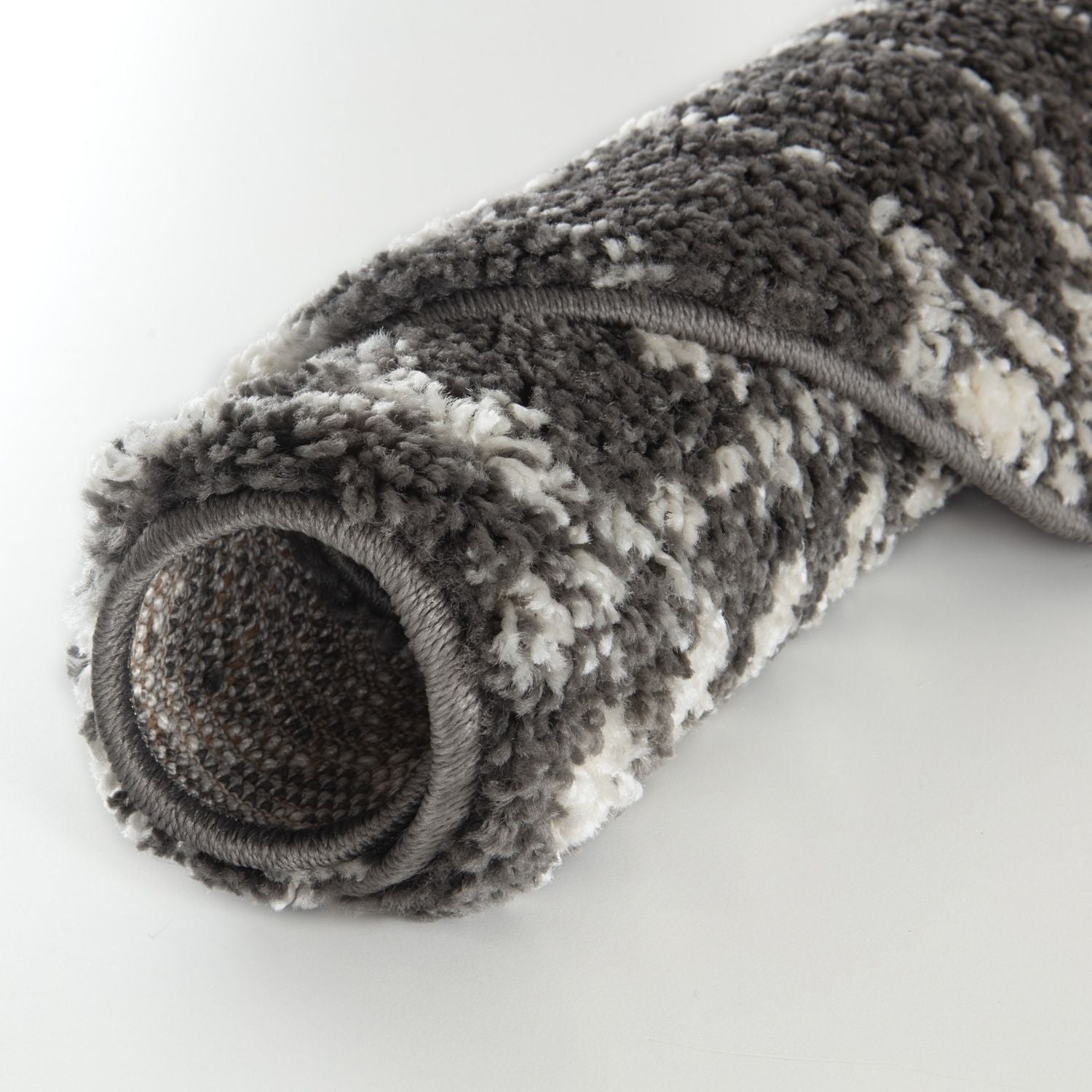 A plush rolled-up moroccan dark grey shaggy rug with textured grey and white pattern perfect for cozy spaces