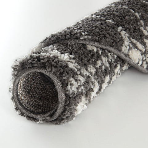 A plush rolled-up moroccan dark grey shaggy rug with textured grey and white pattern perfect for cozy spaces