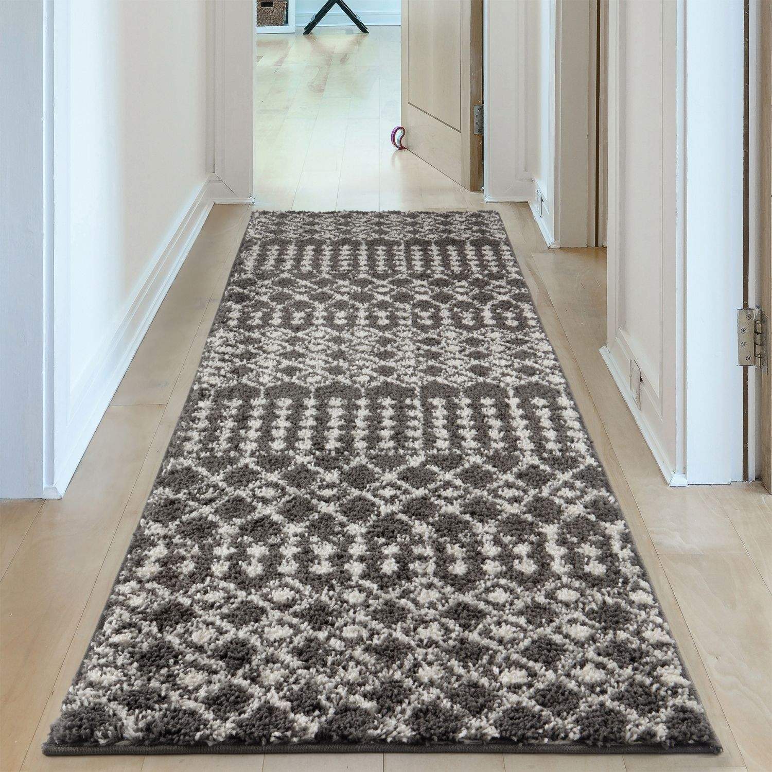A plush moroccan dark grey shaggy runner rug with a geometric pattern in shades of grey and cream