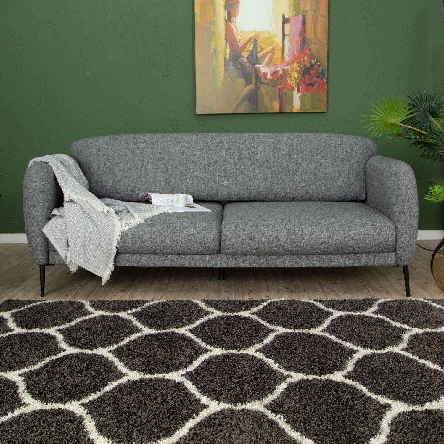 Gray upholstered sofa with sleek black legs sitting on a moroccan dark grey shaggy rug with soft textured fabric finish