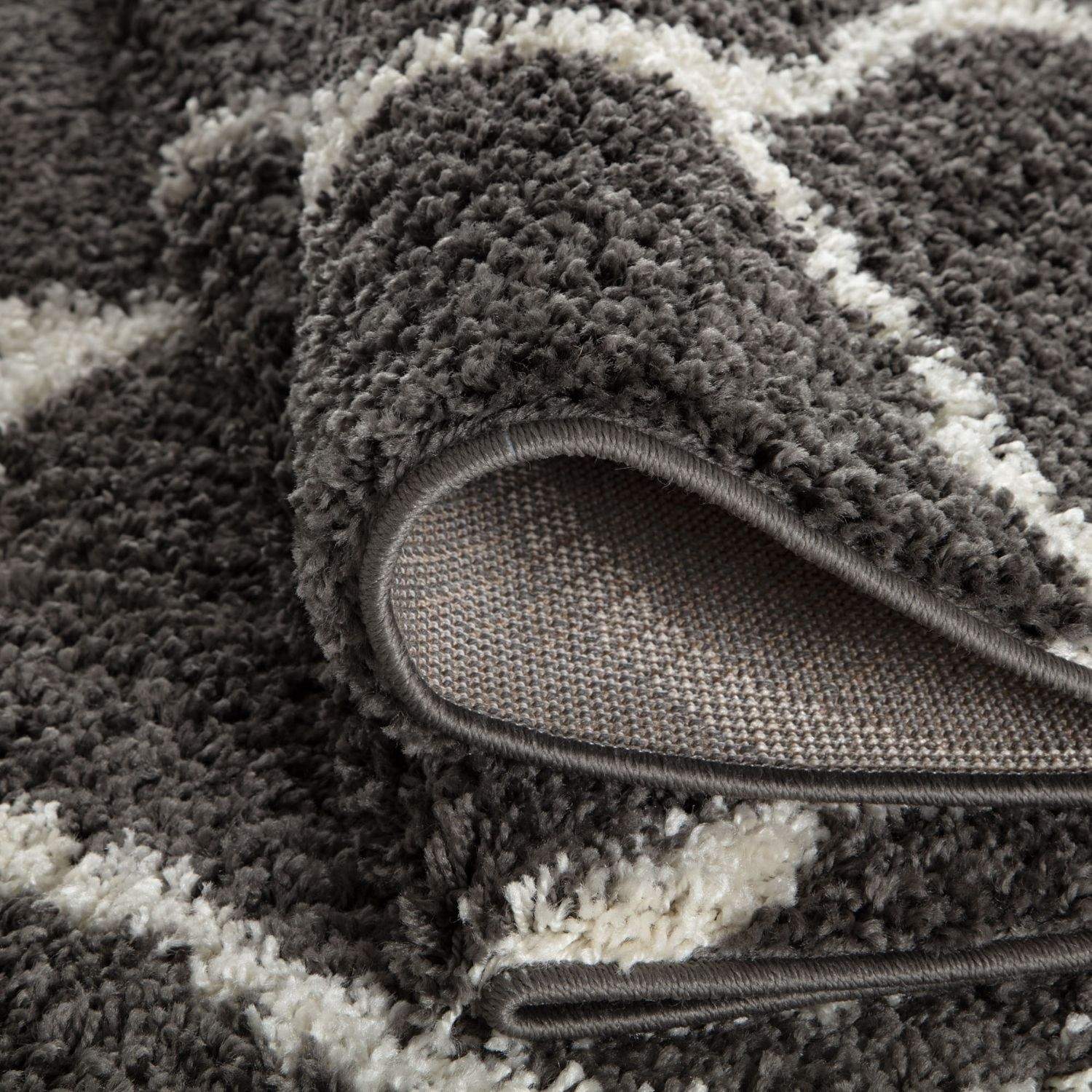 A plush moroccan dark grey shaggy rug with a modern geometric pattern in dark grey and off-white colors