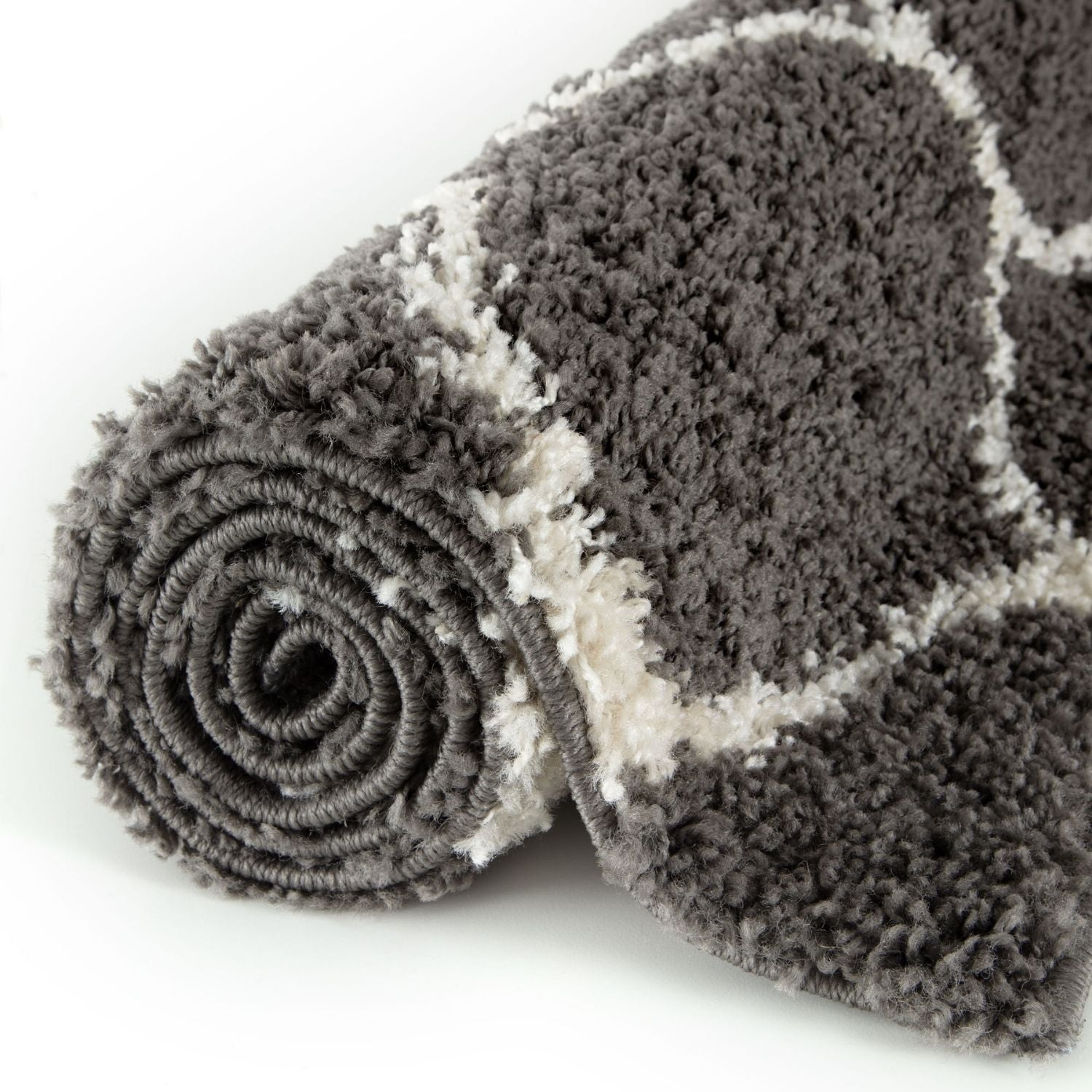A plush moroccan dark grey shaggy rug with a rolled up fluffy textured surface perfect for home decor