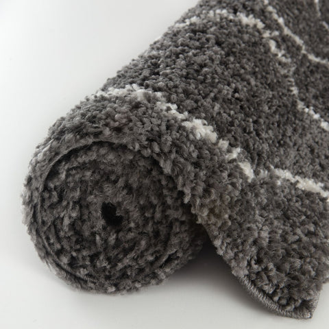 A plush moroccan dark grey shaggy rug rolled up with soft gray and white striped texture for cozy spaces