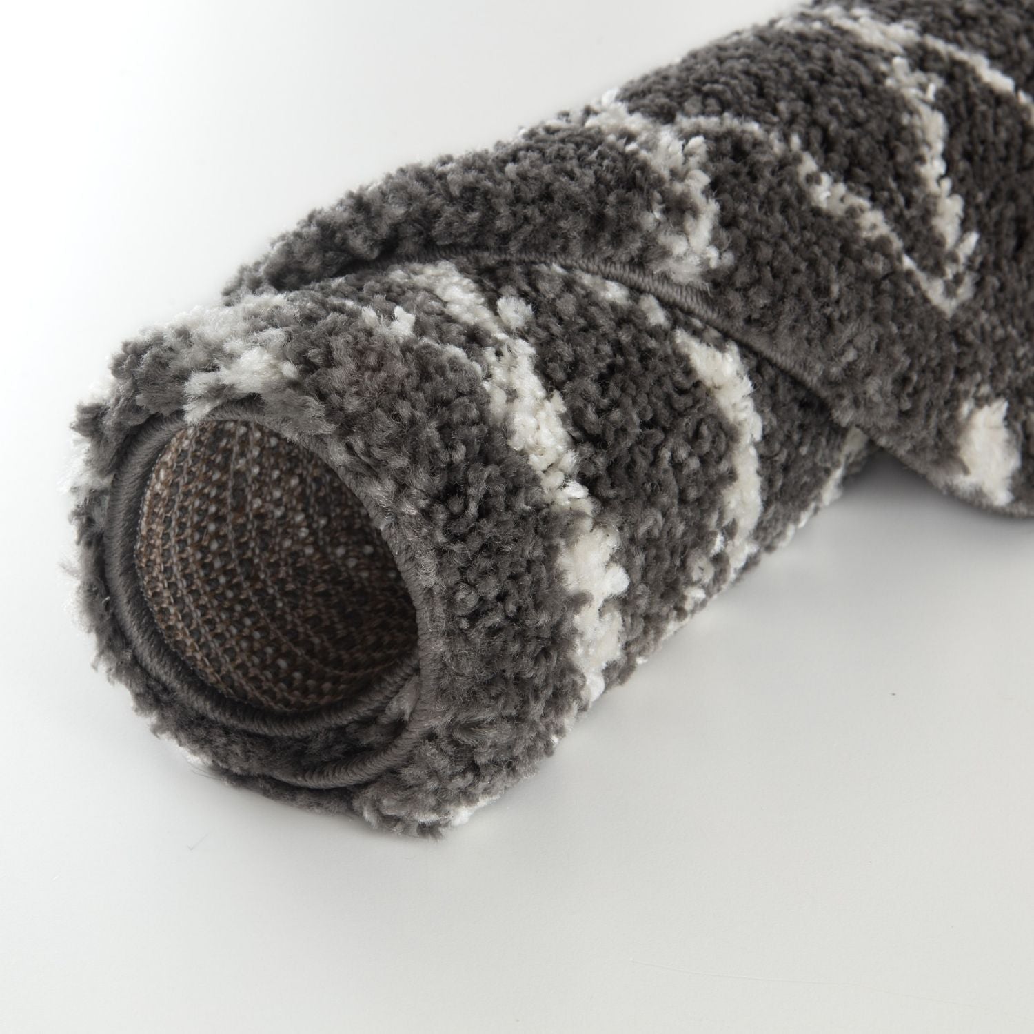 A plush rolled-up moroccan dark grey shaggy rug with a textured looped pile in grey and white stripes