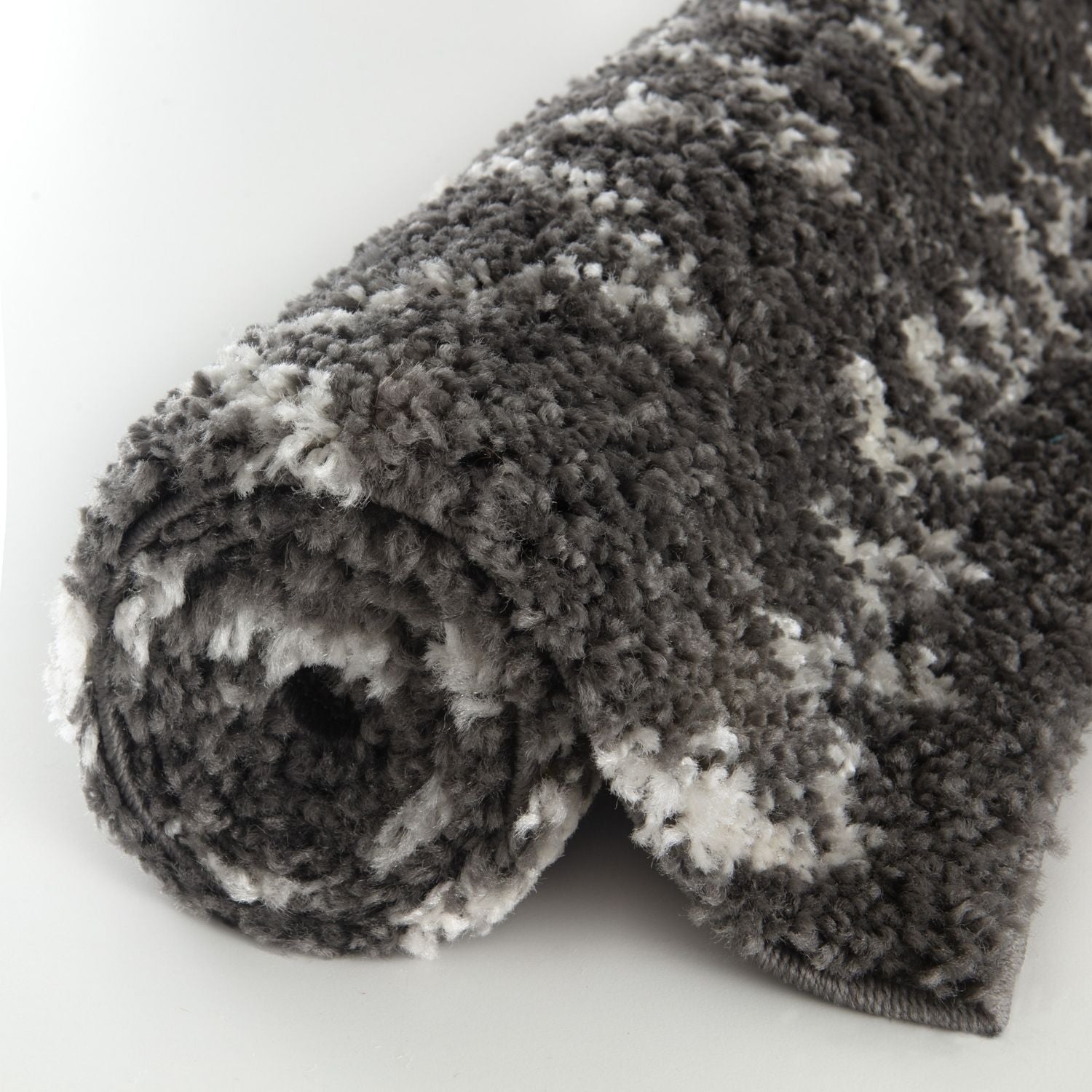 A plush moroccan dark grey shaggy rug rolled up showing its soft textured surface and grey shaggy fibers
