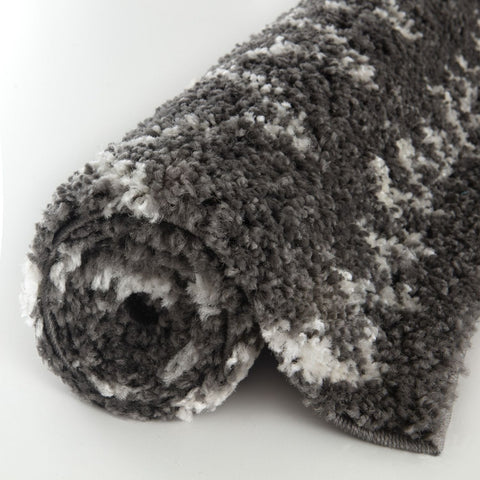 A plush moroccan dark grey shaggy rug rolled up showing its soft textured surface and grey shaggy fibers