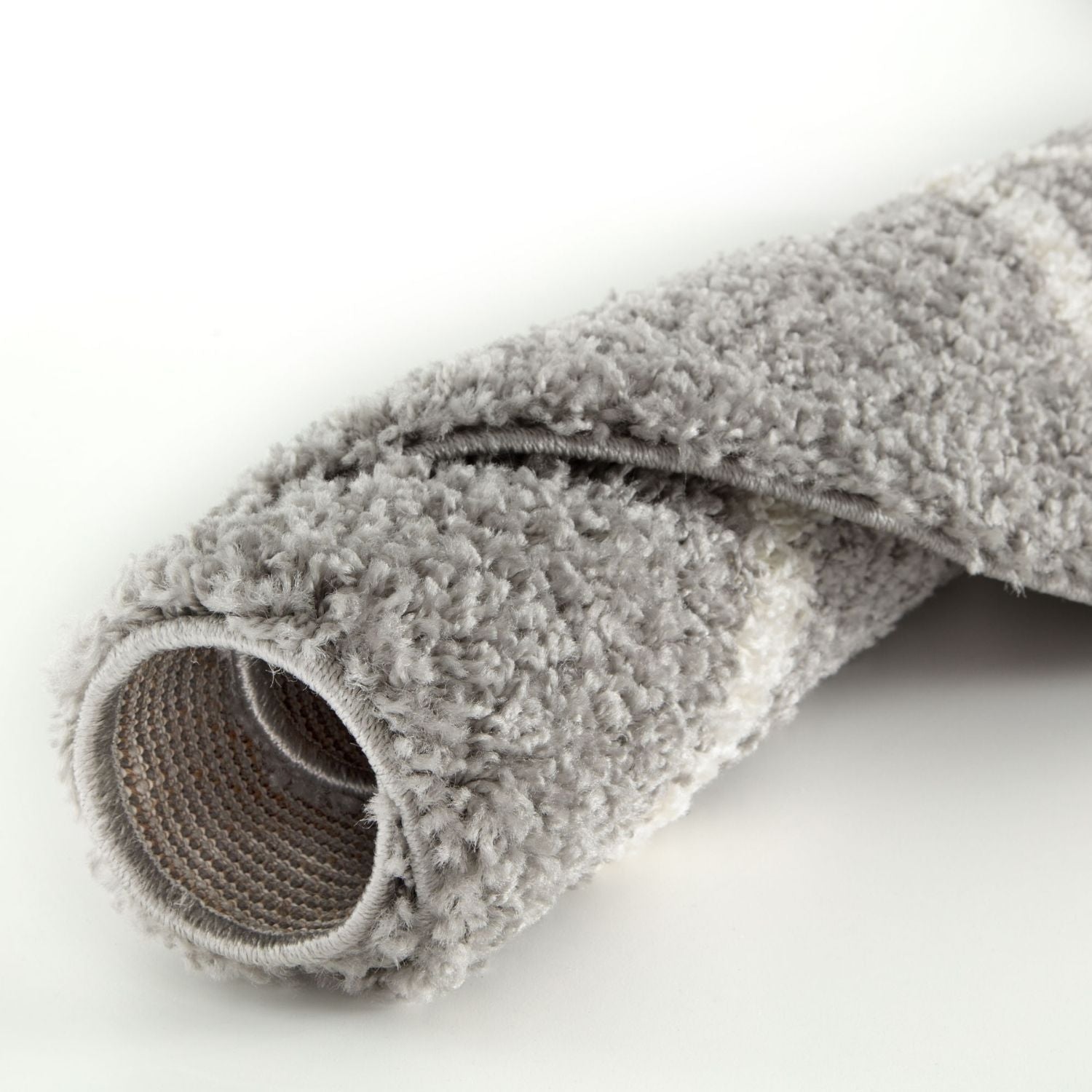 A plush moroccan grey shaggy rug roll with a soft textured surface and visible woven backing shown from the back side
