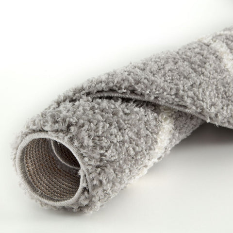 A plush moroccan grey shaggy rug roll with a soft textured surface and visible woven backing shown from the back side