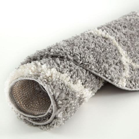 A plush rolled-up moroccan grey shaggy rug with soft textured surface in grey and white tones