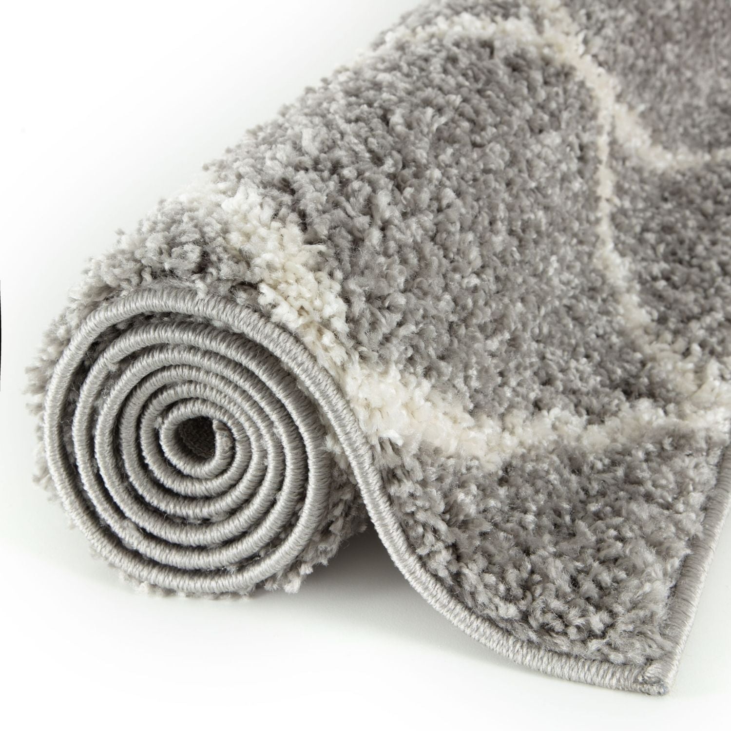 A plush moroccan grey shaggy rug rolled up showing soft textured grey and white shaggy surface