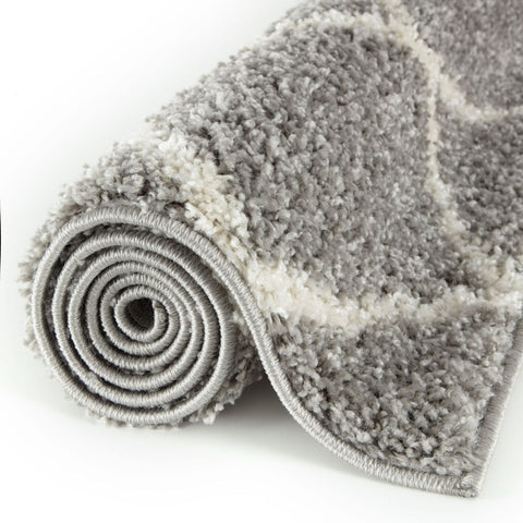 A plush moroccan grey shaggy rug rolled up showing soft textured grey and white shaggy surface