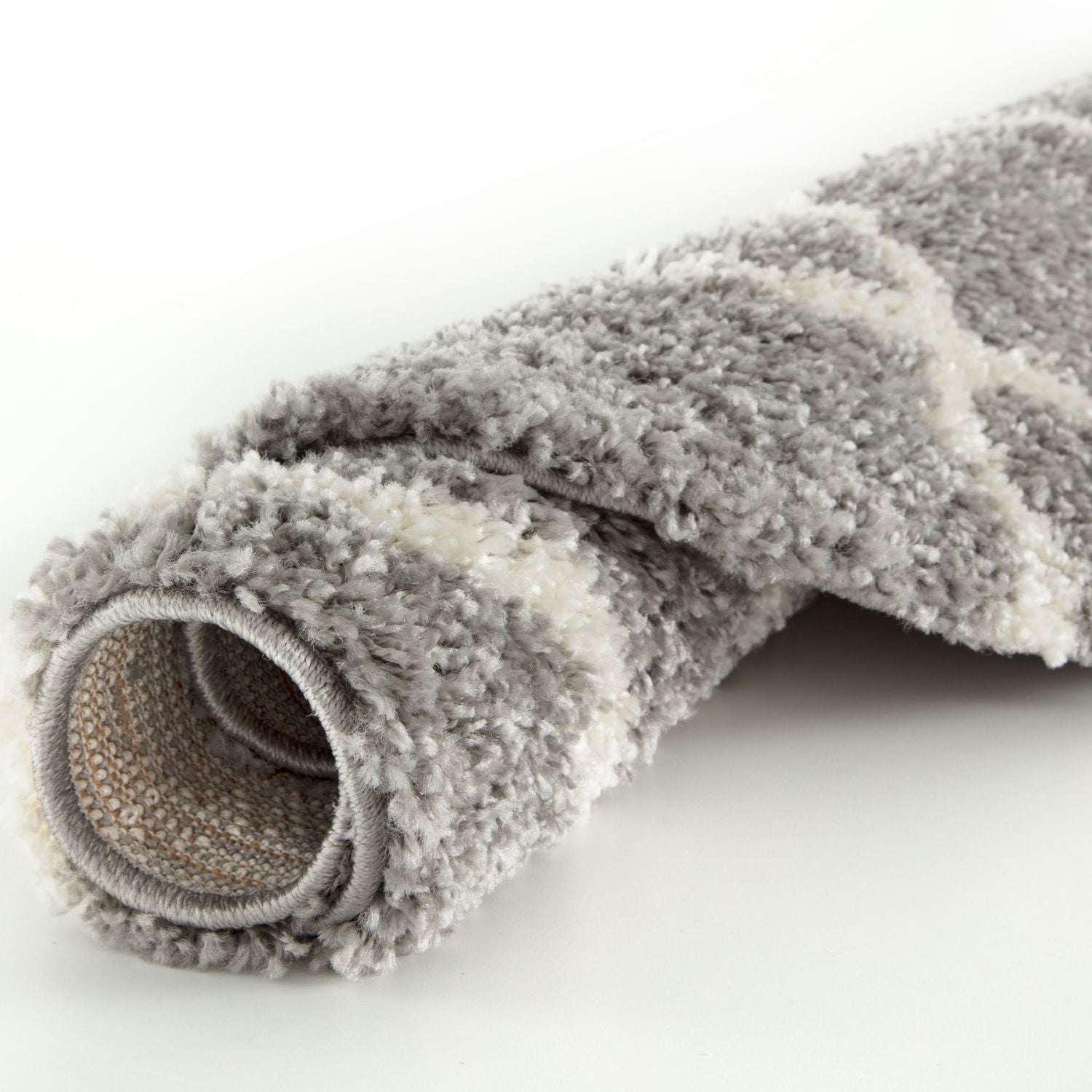 A plush rolled-up moroccan grey shaggy rug with a soft grey and white geometric pattern and shaggy texture