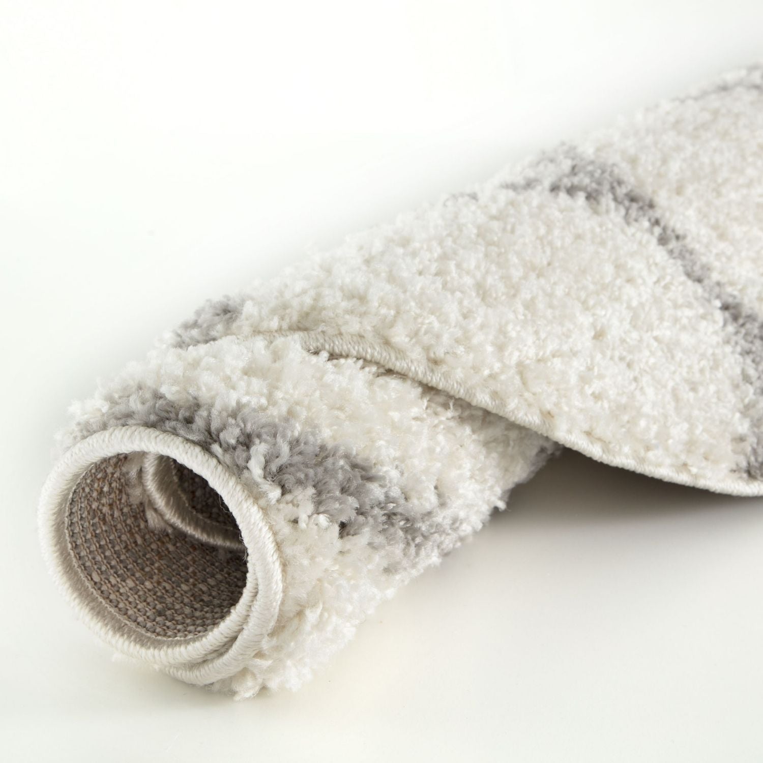 A plush moroccan ivory shaggy rug rolled up with soft white and gray horizontal stripes and a cozy texture
