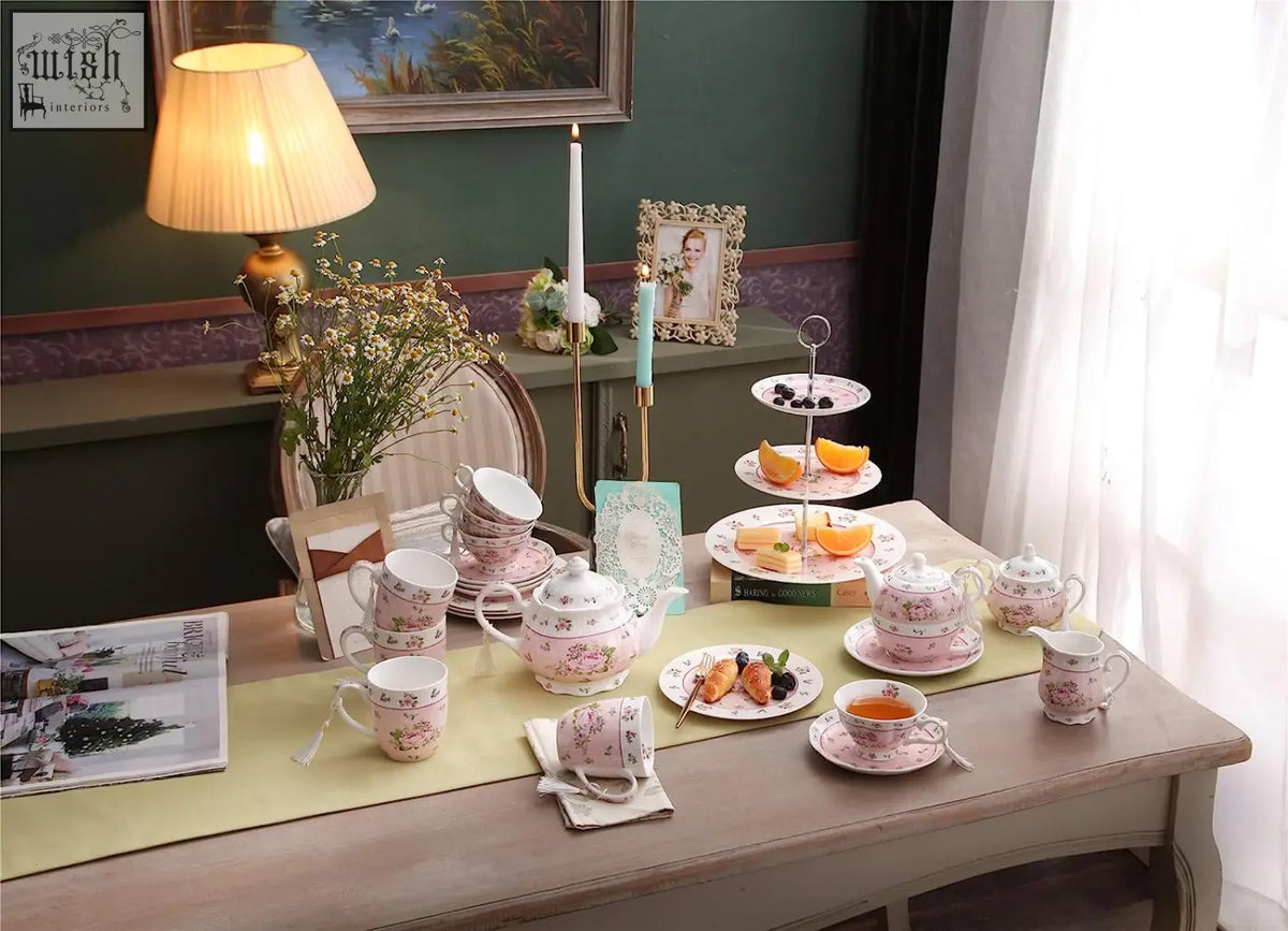 Pink floral porcelain tea set with hand painted patterns and matching saucers alongside a tier cake stand for family party