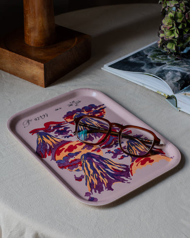 A rectangular wooden mount lucio tray with a pink base and vibrant purple and orange floral design