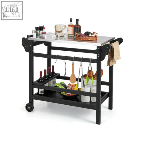 Black metal dining cart table with stainless steel top, wheels, shelves for wine bottles, and hanging utensils for outdoor use