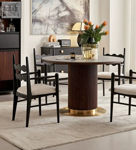 Dark wood round dining table with fluted pedestal base and gold foot paired with mucha dining chair