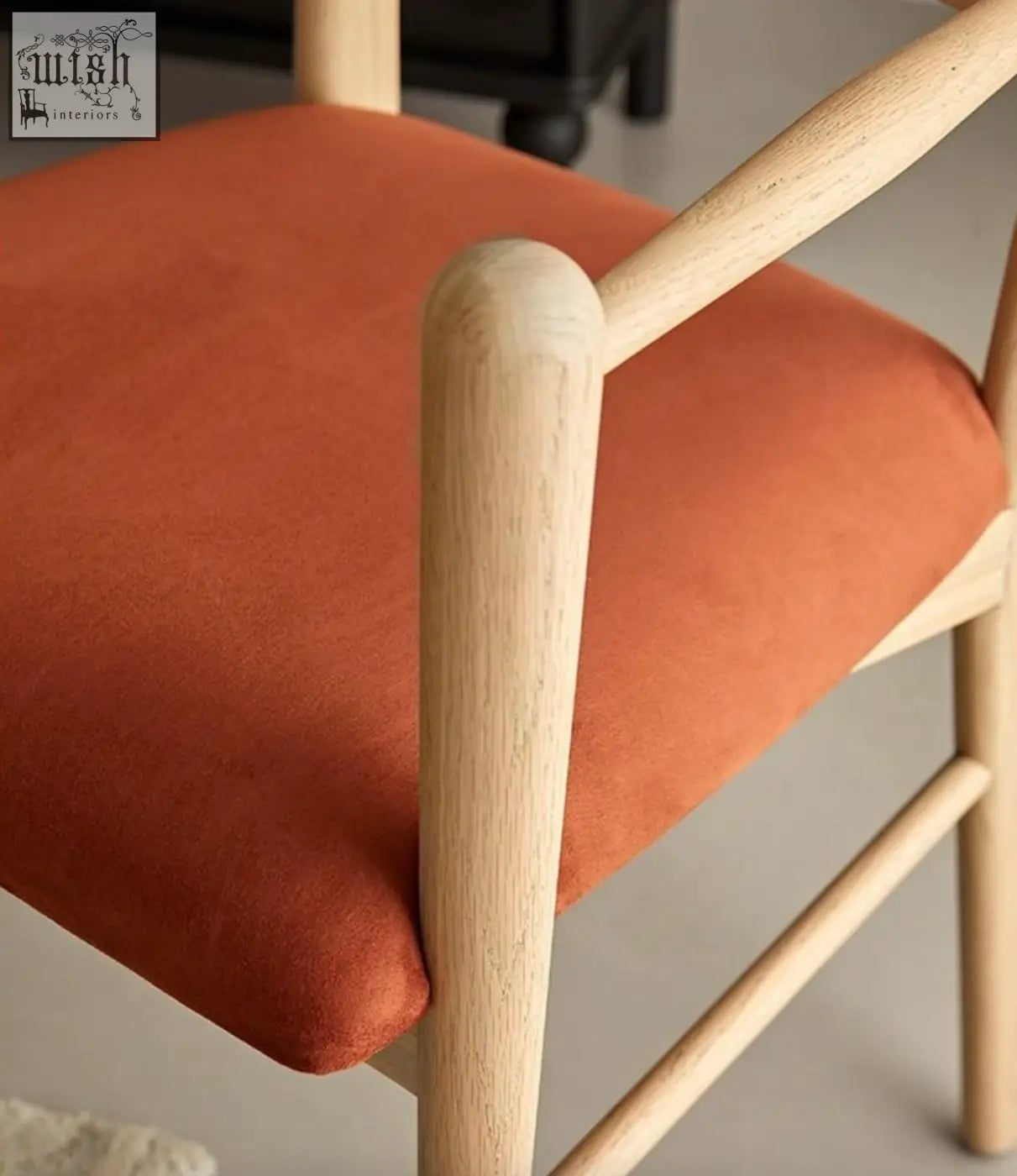 A mucha dining chair with a light wood frame and bright orange upholstered seat perfect for dining areas