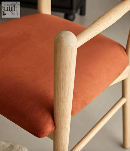A mucha dining chair with a light wood frame and bright orange upholstered seat perfect for dining areas
