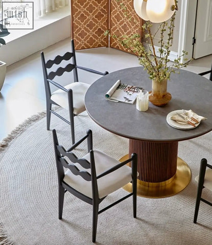 Round gray stone table with fluted bronze base and gold footrest shown with much dining chair seating