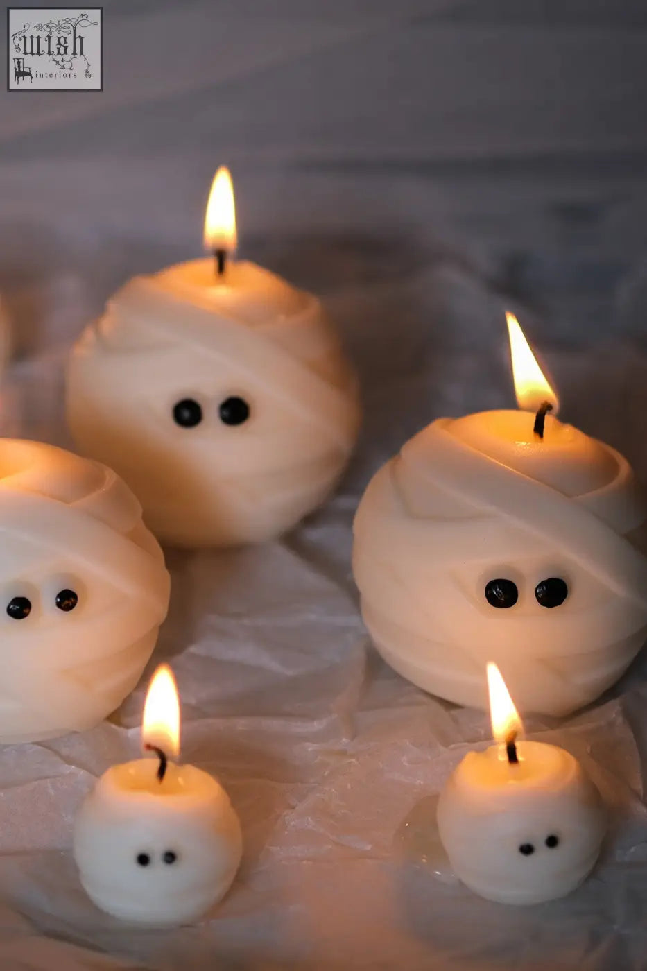 White mummy ghost candles with black bead eyes and lit wicks perfect for spooky decor ghost candles set
