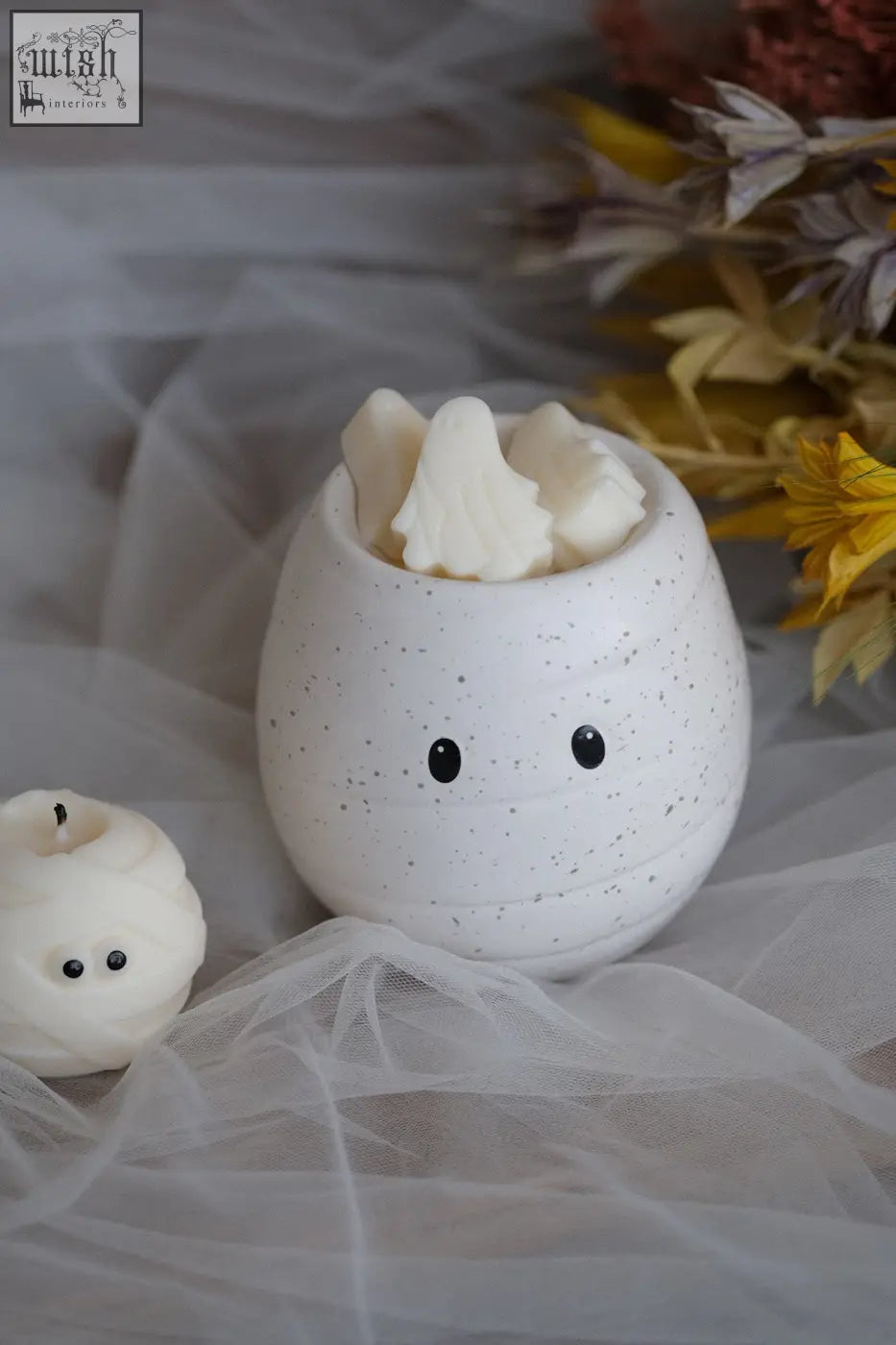 Mummy shaped white speckled ceramic wax melt burner with black eyes holding marshmallows for pumpkin spice oil burner