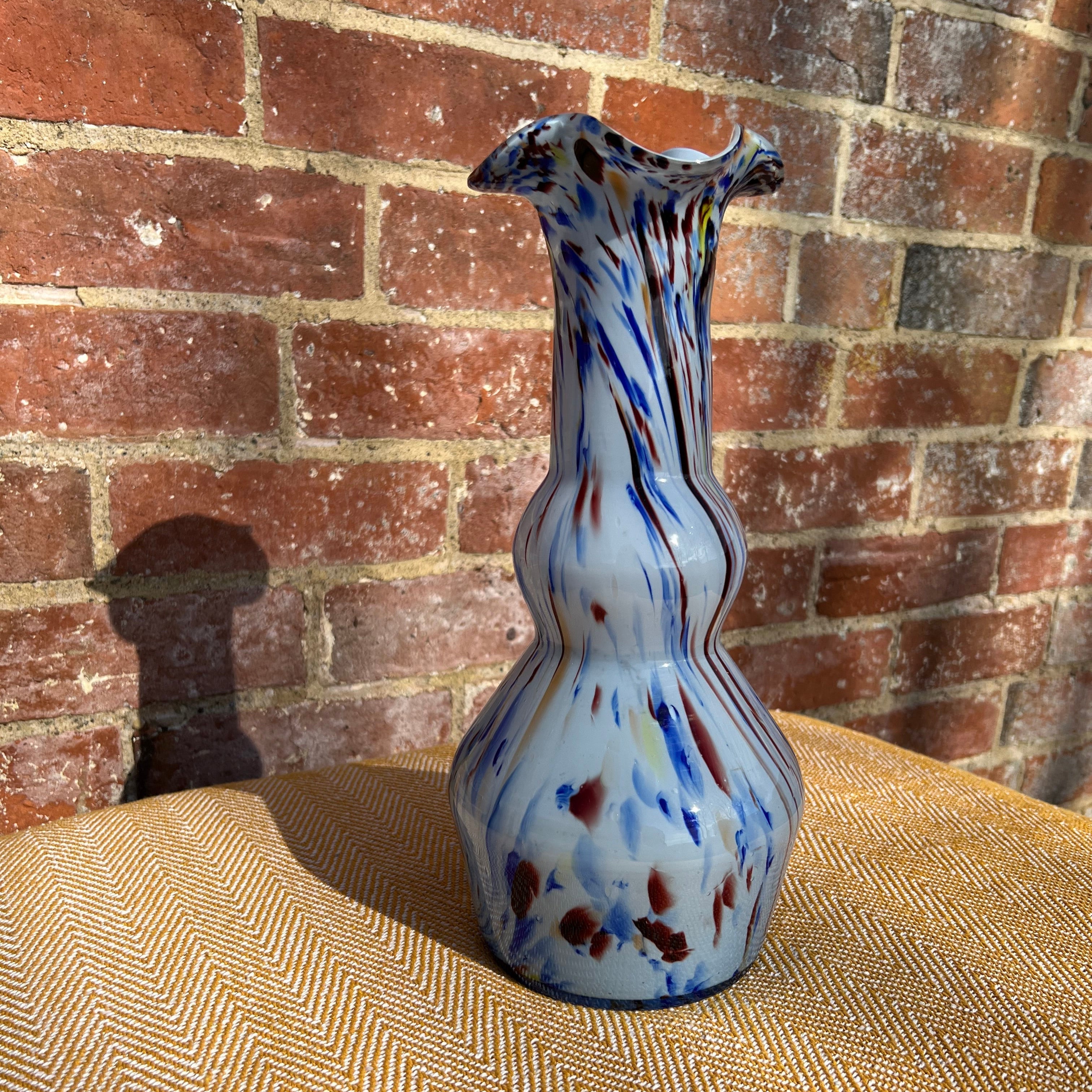 Murano tall glass vase with a fluted rim featuring swirling blue red and yellow patterns on a white base