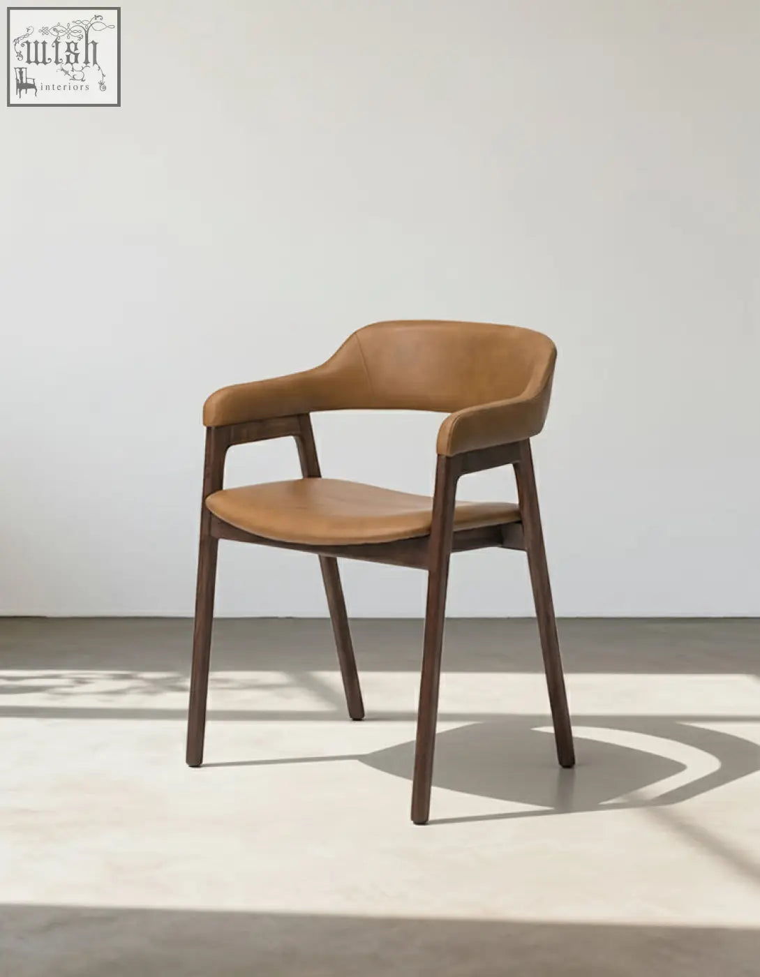 A sleek murcell matching dining chair with tan leather seat and backrest on dark wood legs