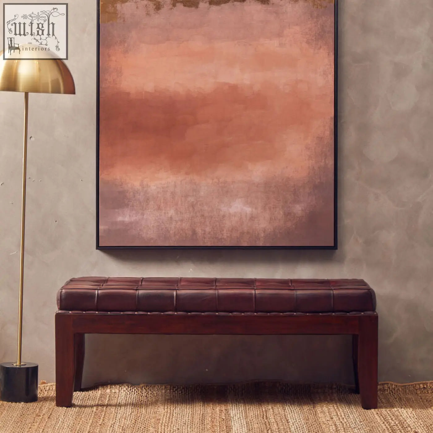 Brown leather tufted bench with dark wood frame shown next to murdoch floor lamp in brushed brass with marble base