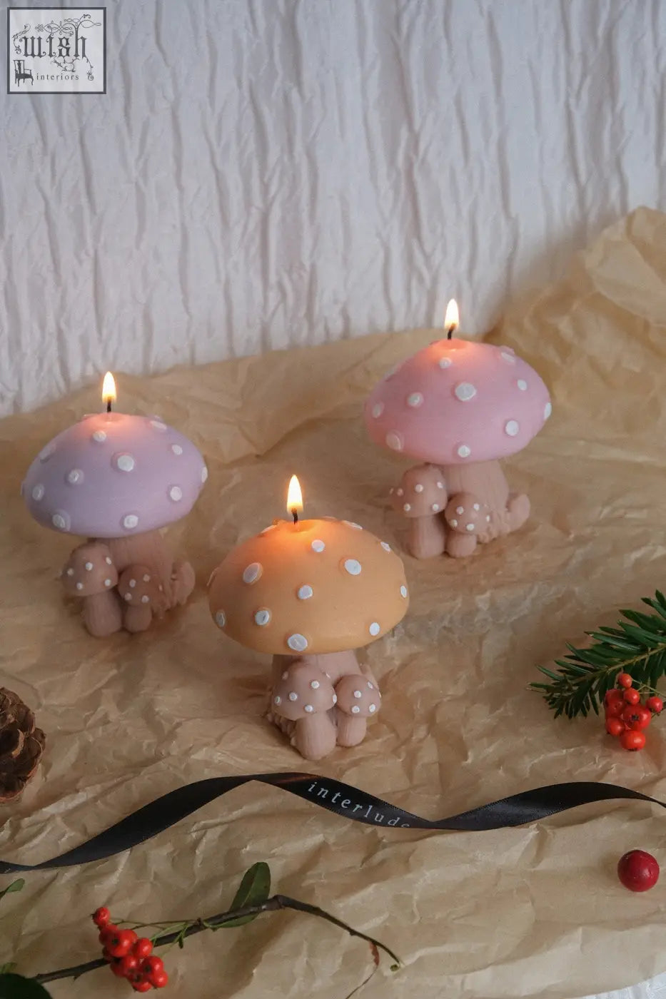 Three whimsical mushroom family candles with pastel pink lavender and peach caps and beige stems with white polka dots