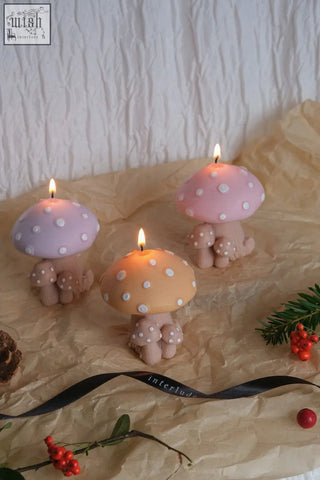 Three whimsical mushroom family candles with pastel pink lavender and peach caps and beige stems with white polka dots