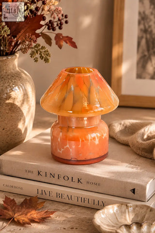 A warm translucent orange mushroom lamp candle with marbled glass pattern highlighting base notes and heart notes