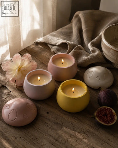 Pastel ceramic mushroom scented candle with handmade jar lid containing lit ylang ylang vanilla musk candle