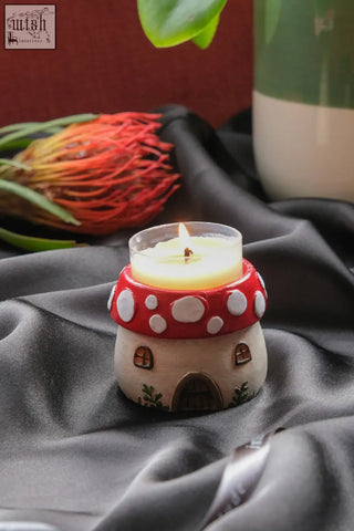 A red and white ceramic mushroom tealight holder with a lit yellow wax candle inside for cozy lighting